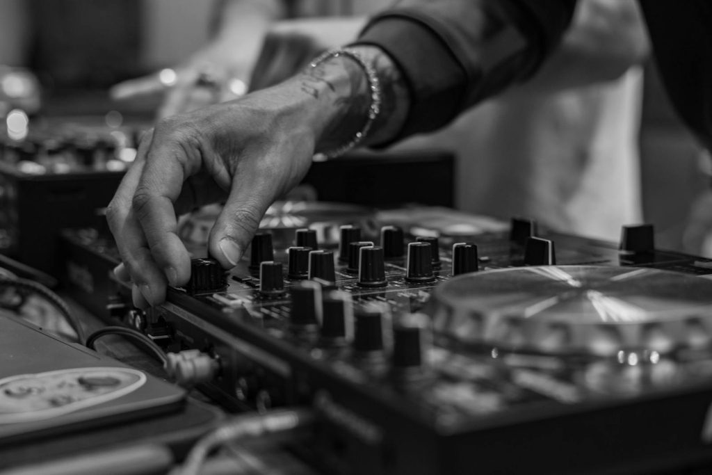 Close-up of a DJ's hand adjusting controls on a mixer, capturing the essence of modern music technology in black and white.